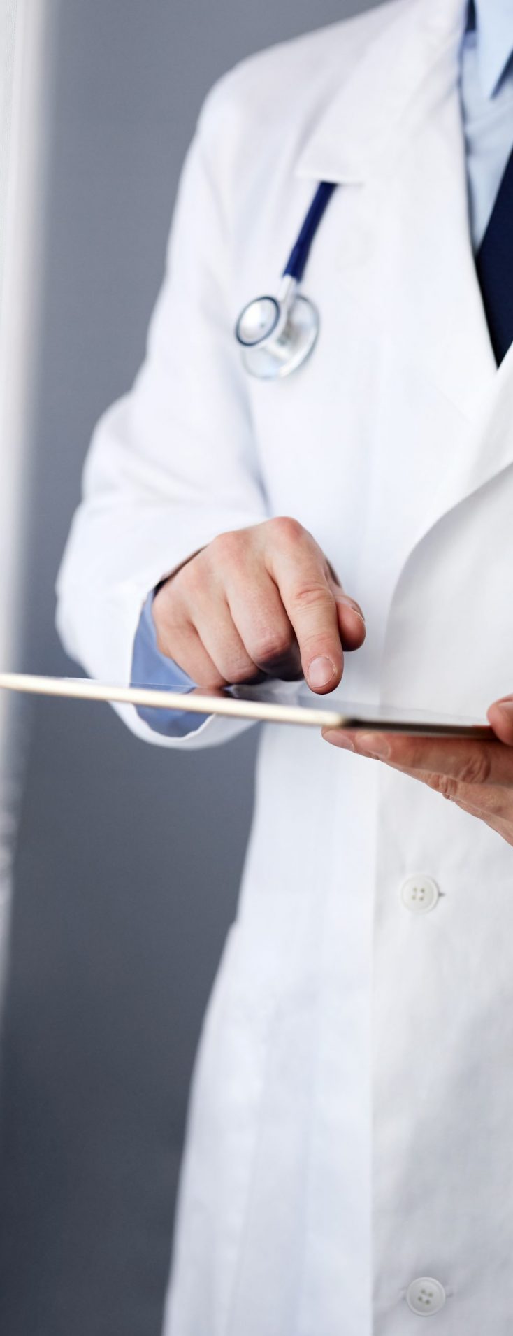 Male doctor working on a digital tablet near a window Male doctor working on a digital tablet near a window